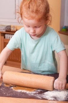 Little girl baking rolling pastry for Christmas cookies