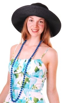 Beautiful young woman in a blue and green dress and pearl chain with an big black straw hat, smiling and looking in the camera, over white.