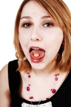 A young teenager girl with her mouth wife open and a pill on her tongue
