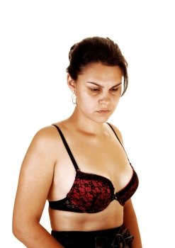 a very sad looking young woman in a portrait shoot in a black skirtand a black and red bra, looking down over white background.