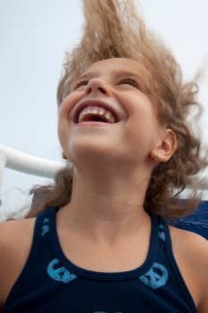 Portrait of cute little girl laughing with her hair blown in the wind.