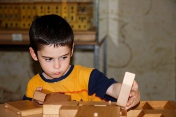 Cute little boy plays with wooden bricks and builds a house. Cute little boy plays with wooden bricks indoors and builds a house