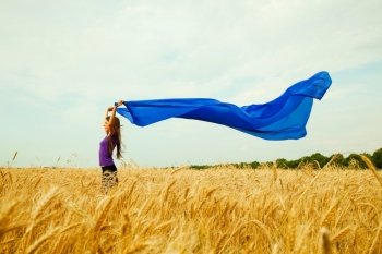 Teen girl at a wheat field with blue fabric