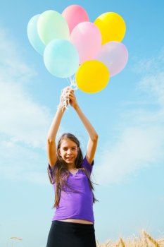 Teen girl at a wheat field with balloons in sunny day