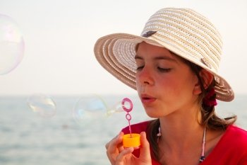 Teen girl blowing bubbles at sea shore