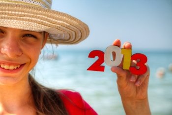 Teen girl at a beach holding wooden number ’2013’