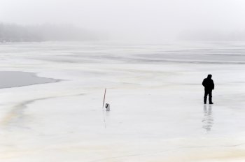 lonely fisherman on frozen river