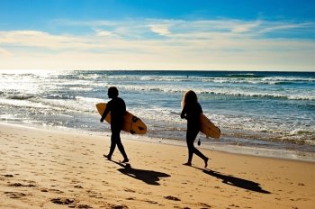 Couple of surfers walking on the ocean beach.  Sagres, Algarve, Portugal