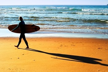 Woman with surfboard walking on the ocean beach. Portugal