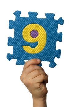 Children hand holding the number Nine. White isolated multicolor number Nine