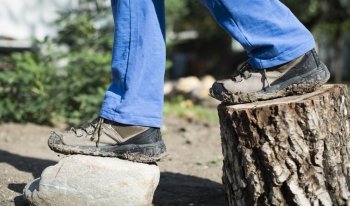 Brown hiking shoes on a stump in the forest
