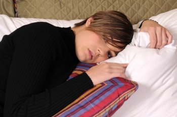 Young woman lying in a hotel bed surrounded by pillows