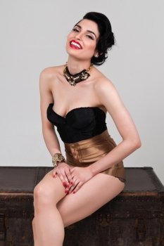 Pretty young brunette in a vintage black bustier and gold shorts