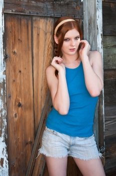 Tall young redhead in a blue top and denim shorts