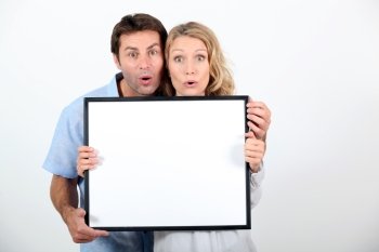 Couple pulling a funny face and holding a blank board ready for your text