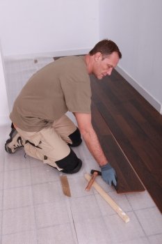 Man at home laying wooden flooring