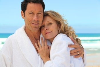 mid aged couple wearing a bathrobe near the sea