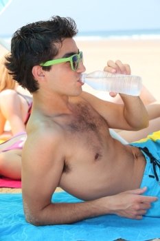 Teenager drinking water on the beach
