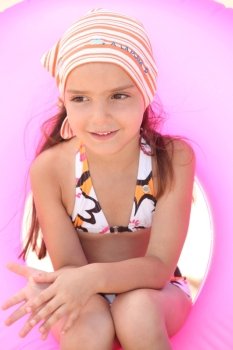 Young girl in bikini sitting in an inflatable beach ring
