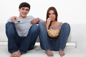 Couple eating popcorn in front of the television