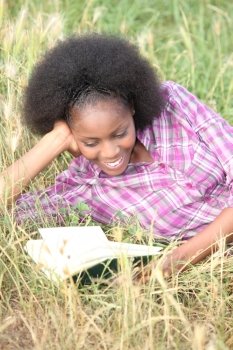Woman reading an amusing book in a field