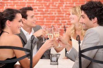 two well dressed couples toasting at the restaurant
