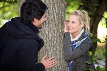 Couple hiding either side of tree