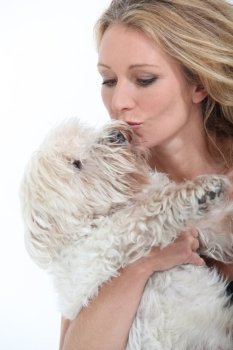 Middle-aged woman kissing dog.