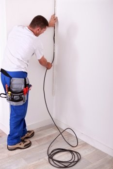 Electrician fixing a wire to a wall