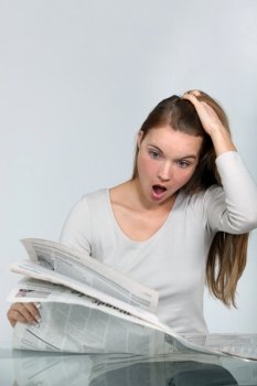 Shocked woman reading a newspaper