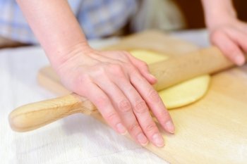 Cooking: woman rolling out the dough on cutting board, close-up shot
