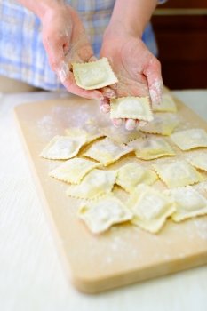 Italian ravioli. Cooking: woman laying out fresh ravioli on a cutting board