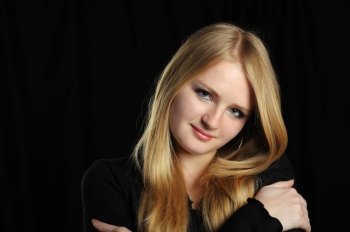 Portrait of the pretty young girl of the blonde. On a black background