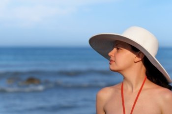 The girl in a hat against the sea and blue sky