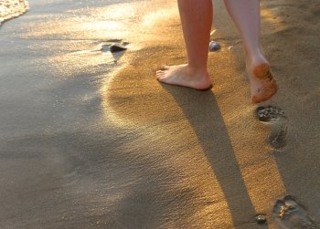 footprint on sand. Sunset illumination, a fragment of female feet