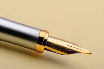 Gold fountain pen closeup. On a yellow paper
