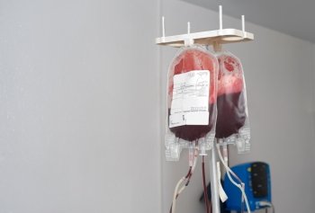 transparent packages hanging on rack are being filled with donor blood, copy space