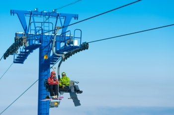 two snowboraders ascend on a ski lift