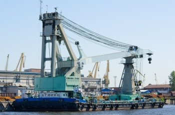 a huge floating crane by a river wharf