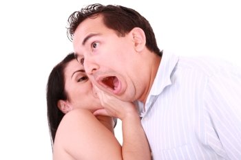 woman tells something into surprised guy’s ear isolated on white background