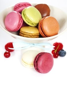 Colorful macaroons in a white plate and fresh berries
