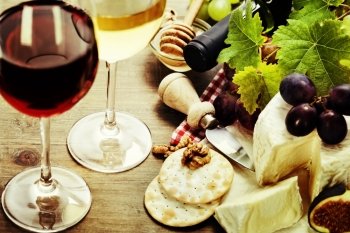 Wine, grape and cheese on wooden background