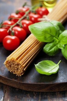 Spaghetti and tomatoes with herbs on an old and vintage wooden table 