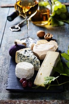  Various types of cheese and white wine on wooden background