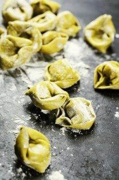 Homemade raw Italian tortellini  prepared and ready for cooking on dark background