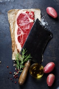 vintage cleaver and raw beef steak on dark background
