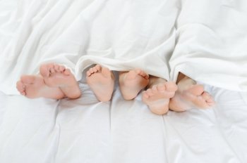 Close-up of the feet of a family on the bed