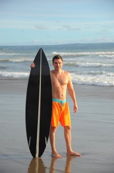 Young surfer with board on the beach