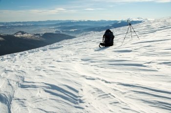 Winter mountain landscape with tourist knapsack and photographic tripod (Ukraine, Carpathian Mt’s, Goverla and Petros Mountains behind)