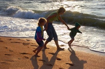 Walking family on evening sandy beach and surf